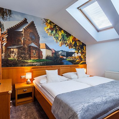 Standardní pokoj hotelu Jelínkova vila - postel, střešní okno a plakát na zdi