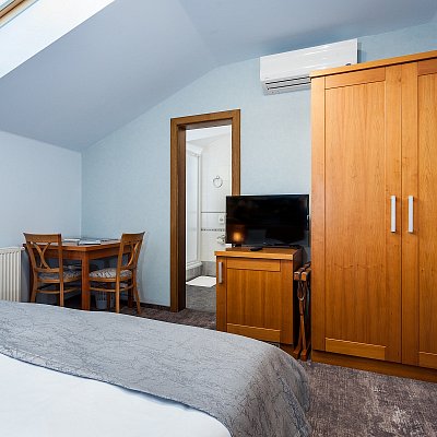 Standardní pokoj hotelu Jelínkova vila - skříň, televize, klimatizace, stůl s židlemi