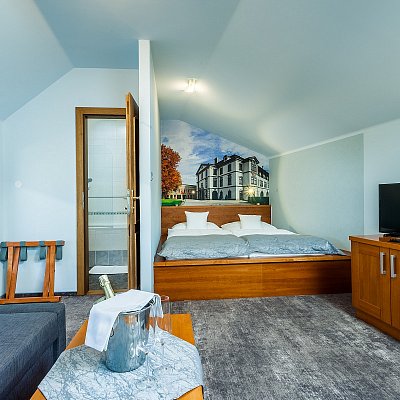 Standardní pokoj hotelu Jelínkova vila - celkový pohled, postel, plakát na zdi, šampaňské na přivítanou